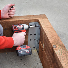 Shot of the bracket being installed on some timber sleepers, a man using a drill is visible.