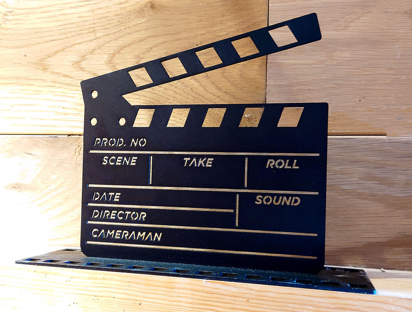 Clapper Board Ornament from At the Movies collection - made from steel with a black finish, posed on a wooden surface with a wooden wall.
