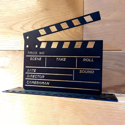 Clapper Board Ornament from At the Movies collection - made from steel with a black finish, posed on a wooden surface with a wooden wall.