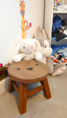 Footstool with Happy Bear Design next to rabbit plush toys
