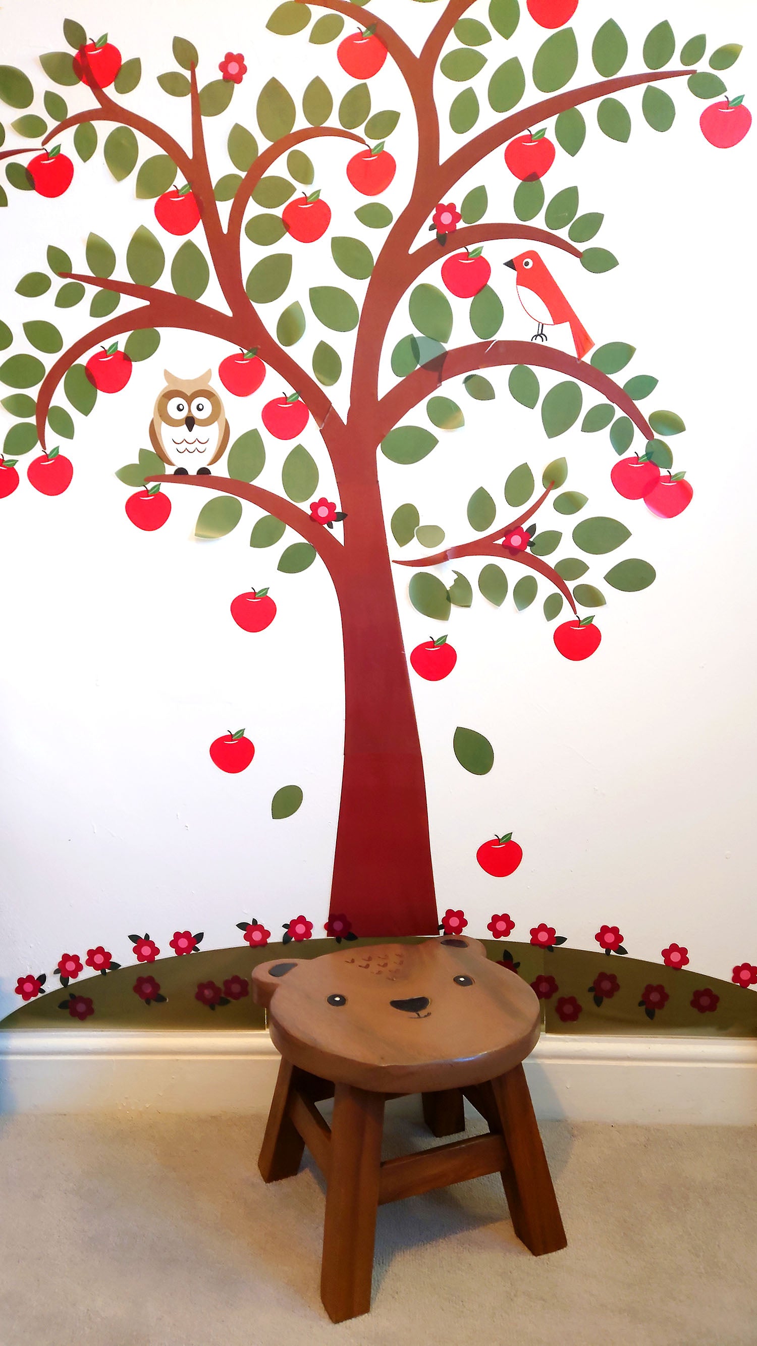 wooden footstool with bear design, in front of wall with tree painted on