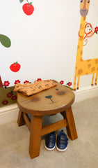 Wooden Footstool with smiling cat design with children's clothes on top