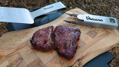 Cooked steak is served on a wooden chopping board using the Volcann Stainless Steel tools