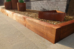 Corner join of Brown-Treated Dark Brown LightGauge Sleeper positioned on some stones outside