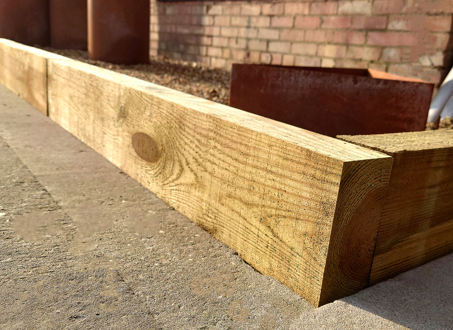 Closeup of the corner joint of 2 Timber Railway Sleepers being used as driveway edging between a concrete surface and stones