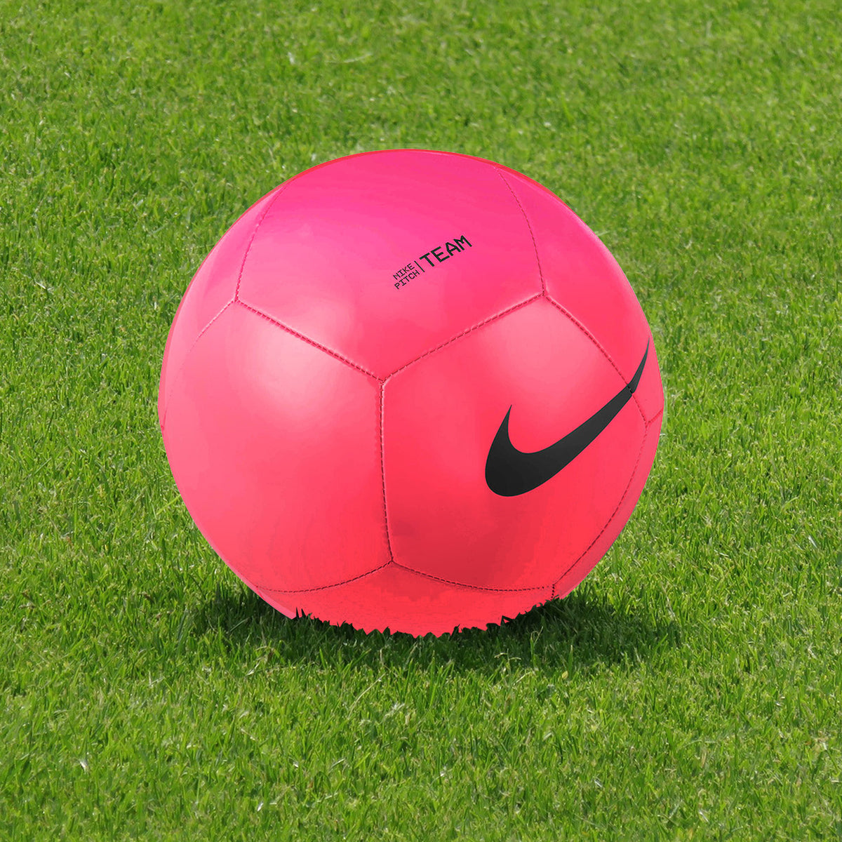 Nike Pitch Team Football - Bright Pink Finish - Ball Positioned on Turf on Modern Football Pitch