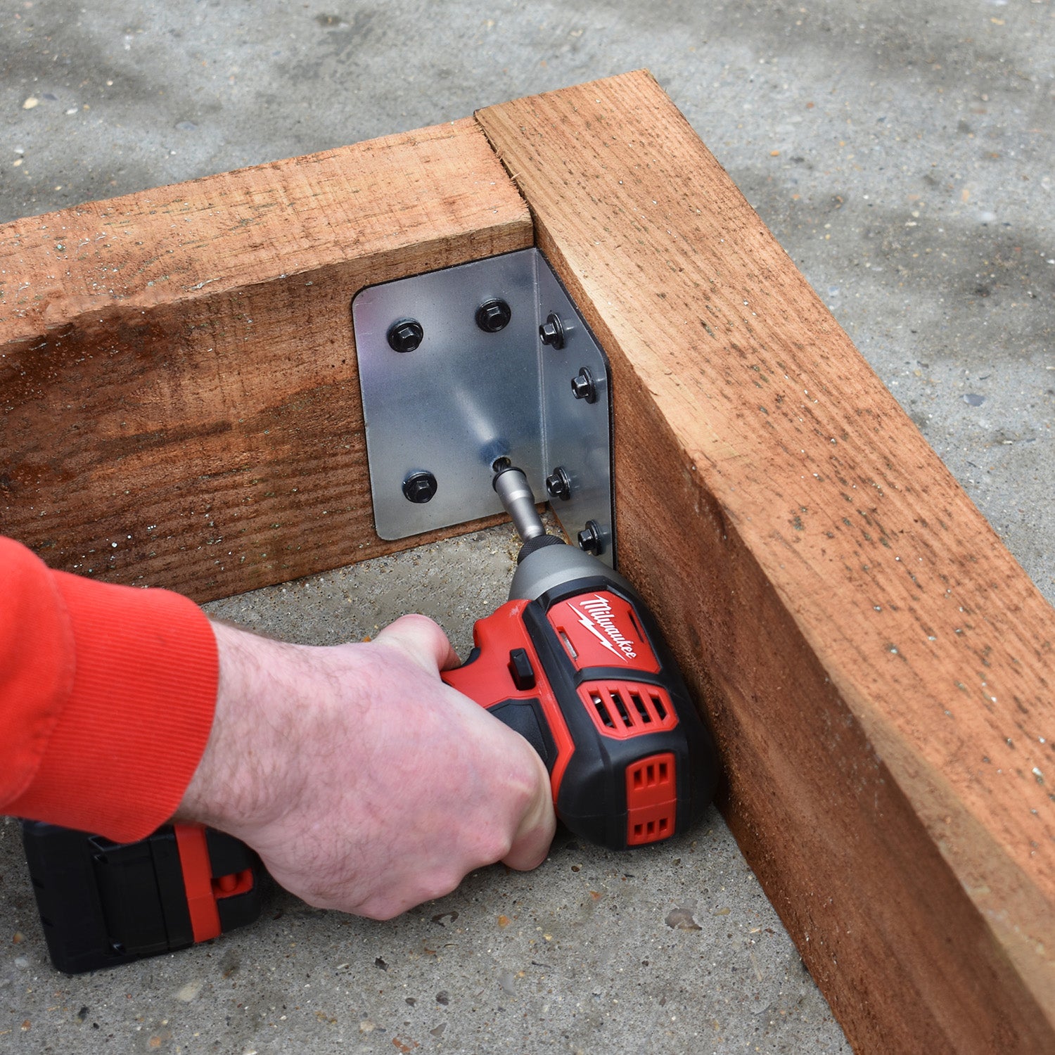 Shot of the bracket being installed on some timber sleepers, a man using a drill is visible.